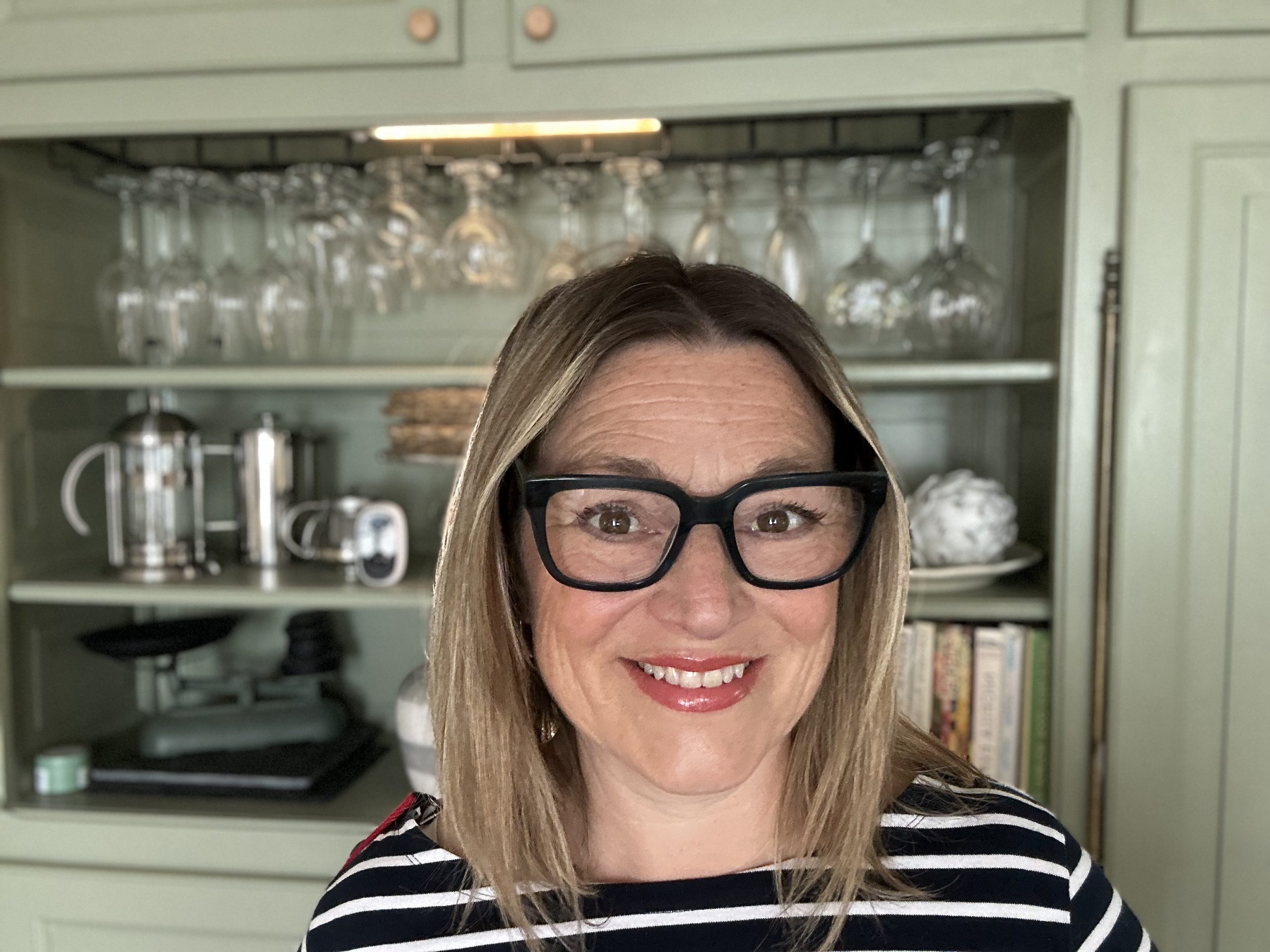 Lucy smiling at camera in her kitchen wearing a breton stripe t shirt